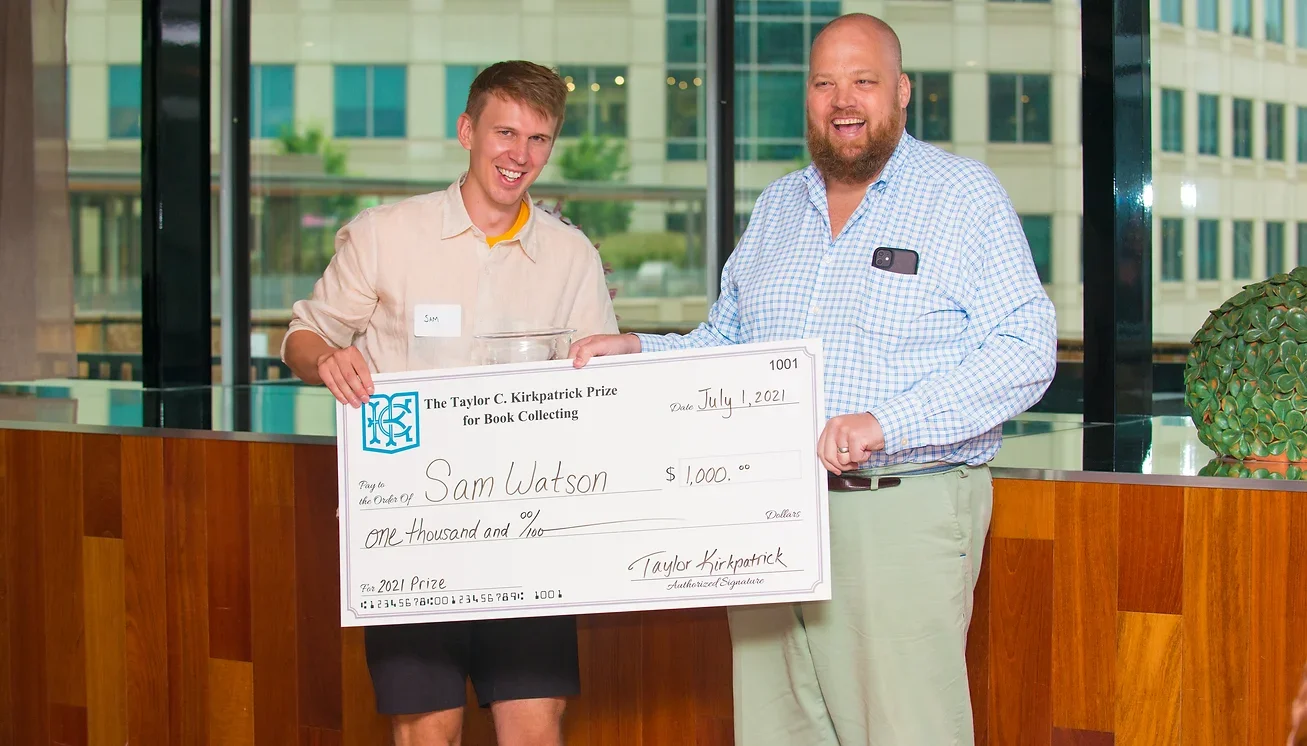 Sam Watson and Taylor Kirkpatrick pose with Watson's check for winning the Kirkpatrick Book Collecting Prize in 2021