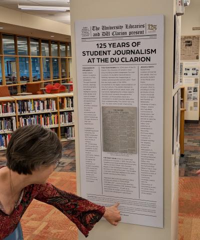 Image of the introduction panel of the exhibit with someone pointing something out in the text.